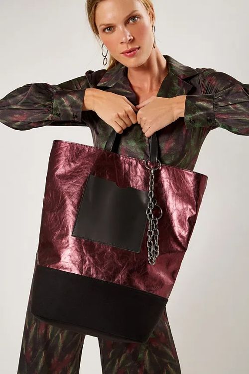 mulher segurando bolsa lateral vinho metálico 